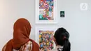 Pengunjung menyaksikan karya lukis yang bertajuk 'Membangun Harmoni' di Museum Basoeki Abdullah, Jakarta, Sabtu (18/12/2021). 'Membangun Harmoni' tersebut merupakan hasil karya lomba dari pelajar di tingkat SD, SMP, hingga SMA. (Liputan6.com/Herman Zakharia)