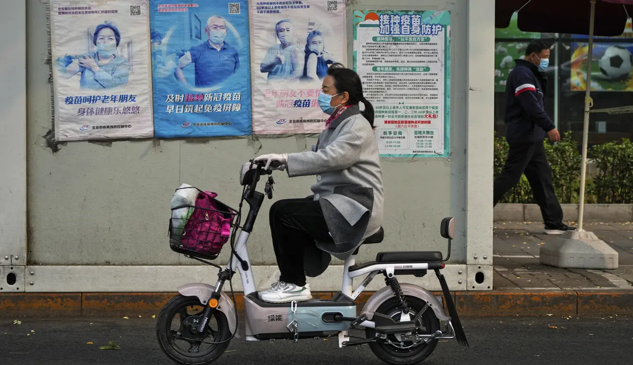 Seorang wanita melewati fasilitas pengujian virus corona yang memajang poster yang mempromosikan vaksinasi COVID-19 di Beijing, Rabu (26/10/2022). Kota Shanghai di China mulai memberikan vaksin COVID-19 yang dapat dihirup pada hari Rabu di tempat yang tampaknya menjadi yang pertama di dunia. (AP Photo/Andy Wong)