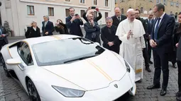 Paus Fransiskus saat menerima hadiah mobil Lamborghini Huracan di Vatikan, Rabu (15/11). Mobil Lamborghini ini oleh Paus rencananya akan dilelang dan hasilnya akan digunakan untuk membantu jemaah Kristen di Irak. (L'Osservatore Romano/Pool Photo via AP)