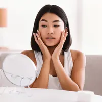 Ilustrasi seorang perempuan yang konsisten menerapkan rutinitas minimalis untuk meredakan breakout akibat over skincare. ©Milkos/Depositphotos