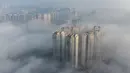 Foto udara ini menunjukkan bangunan yang diselimuti kabut pagi di Bijie, provinsi Guizhou barat daya China (18/11/2021).  Bijie memiliki iklim dataran tinggi subtropis dengan musim panas yang sangat hangat dan hujan serta musim dingin yang sejuk dan lembap. (AFP/STR)
