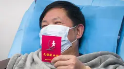Pasien yang pulih dari coronavirus memegang sertifikat donor darah saat menyumbang plasma di Wuhan (17/2/2020). Pasien sembuh diimbau menyumbangkan plasma karena hasil awal mengindikasikan efektivitas produk terapeutik plasma konvalesen dalam mengobati pasien dengan kondisi kritis. (Xinhua/Cai Yang)
