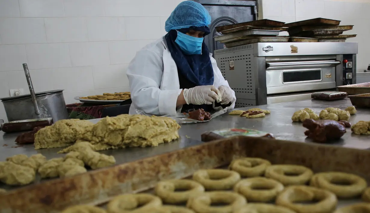 Seorang perempuan Palestina menyiapkan kue tradisional untuk dijual di asosiasi wanita setempat menjelang Idul Fitri untuk merayakan akhir bulan Ramadan di tengah karantina wilayah (lockdown) akibat epidemi COVID-19 di Kota Beit Lahia, Jalur Gaza utara, pada 17 Mei 2020. (Xinhua/Rizek Abdeljawad)