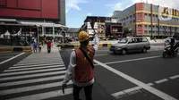 Petugas mengatur lalu lintas untuk warga menyeberang jalan menggunakan pelican crossing di kawasan Glodok, Jakarta, Sabtu (22/1/2022). PT Transportasi mulai mengoperasikan Halte Glodok baru dengan rute Blok M - Kota (Koridor 1). (Liputan6.com/Johan Tallo)