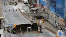 Petugas keselamatan darurat melihat sinkhole besar di Rideau Street, Ottawa, Kanada, Rabu (8/6). Awalnya sebuah lubang berdiameter 5 meter dilaporkan menganga, lalu sinkhole makin membesar hingga mencakup seluruh jalur dan trotoar. (REUTERS/Chris Wattie)