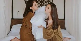 Jessica Mila dan Enzy Storia, dua member geng Blackpunk yang baru saja menikah memang telah lama terlihat sangat kompak. Di atas sebuah bed hotel, keduanya tampil seru mengenakan bathrobe berwarna cokelat. Foto: Instagram.