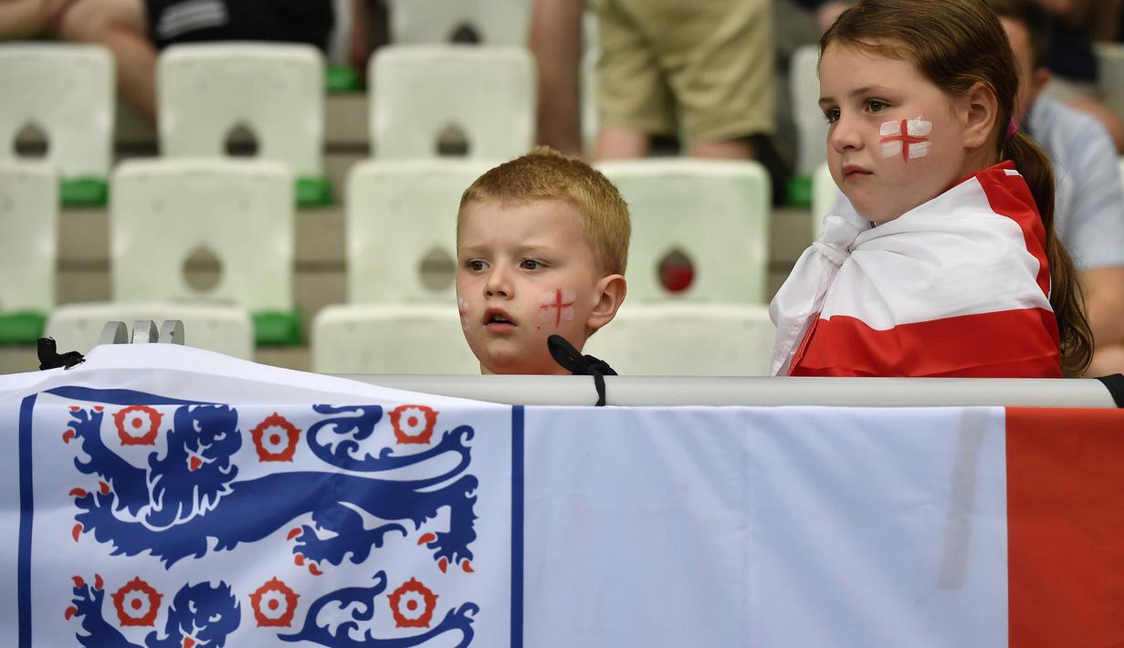 Dua suporter cilik asal Inggris tengah serius mnyaksikan laga timnya melawan Slovakia pada piala Eropa 2016 di Stadion Geoffroy-Guichard, Saint-Etienne,(20/6/2016). (AFP/Jeff Pachoud)
