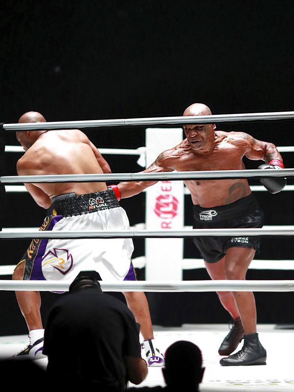 Mike Tyson melakukan pukulan terhadap Roy Jones Jr pada pertarungan tinju eksibisi di Los Angeles, Amerika Serikat, Sabtu (28/11/2020). Pertandingan berakhir tanpa pemenang alias imbang. (Joe Scarnici/Triller via AP)