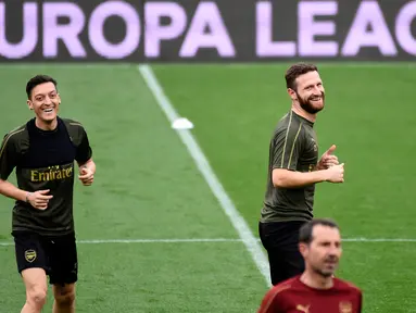 Gelandang Arsenal asal Jerman, Mesut Ozil (kanan) dan bek Shkodran Mustafi melakukan pemanasan selama sesi latihan tim di stadion Mestalla di Valencia, Spanyol (8/5/2019). Arsenal akan bertanding melawan Valencia pada leg kedua babak semifinal Liga Europa di Mestalla. (AFP Photo/Jose Jordan)