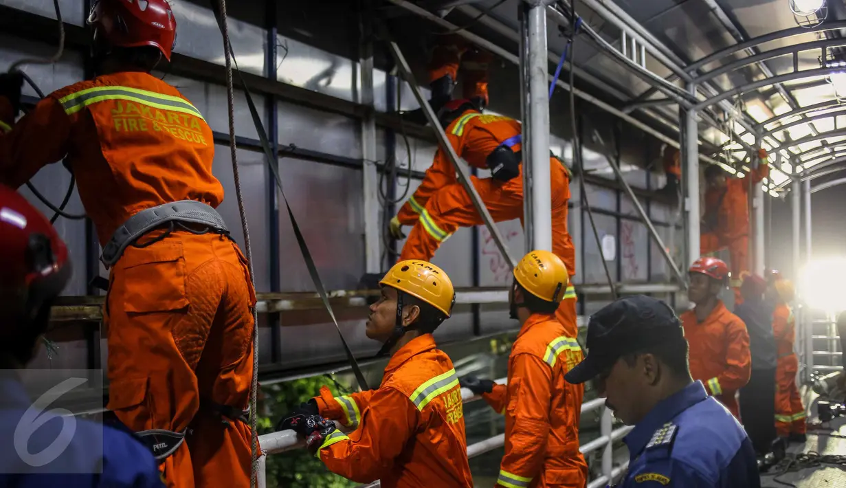 Petugas damkar berusaha melepaskan papan reklame yang terpasang di JPO kawasan Salemba, Jakarta, Rabu (26/10) malam. Pembongkaran dalam rangka penertiban terpadu yang dilakukan oleh petugas gabungan dari Pemprov DKI Jakarta. (Liputan6.com/Faizal Fanani)