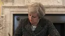 PM Inggris Theresa May saat akan menandatangani surat permohonan Artikel 50 di 10 Downing Street, London, Selasa (28/3). Penandatangan ini secara resmi memulai proses keluarnya Inggris dari keanggotaan Uni Eropa atau Brexit. (Christopher Furlong/Pool/AFP)