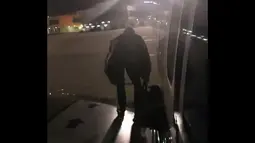 Seorang penumpang maskapai Ryanair keluar lewat pintu darurat di sayap pesawat di Bandara Malaga, Spanyol, Rabu (3/1). Pria berkebangsaan Polandia itu lalu santai saja duduk di pesawat, meletakkan tas di sampingnya. (Fernando Del Valle/AFP)