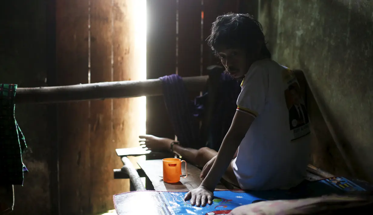 Seorang pria yang menderita penyakit mental duduk dirantai di tempat tidur kamarnya di dalam rumah keluarganya di Curug Sulanjana Desa penginapan Serang, Provinsi Banten, Indonesia (23/3). (REUTERS/Beawiharta)