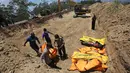 Petugas membawa jenazah korban gempa dan tsunami untuk dimakamkan massal di Palu, Sulawesi Tengah, Senin (1/10). (AP Photo/Tatan Syuflana)