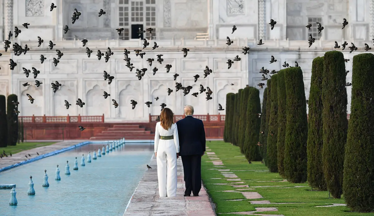 Presiden AS Donald Trump dan Ibu Negara Melania Trump berjalan saat mengunjungi Taj Mahal di Agra, India, Senin (24/2/2020). Kunjungan Donald Trump bertujuan memperdalam hubungan antara Amerika Serikat dan India. (Mandel NGAN/AFP)