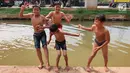 Anak-anak bermain dan berenang di Sungai Kalimalang, Jakarta Timur, Jumat (5/7/2019). Tingginya suhu udara Ibu Kota akibat musim kemarau menyebabkan anak-anak tersebut berenang di Sungai Kalimalang meski dengan kondisi seadanya. (Liputan6.com/Immanuel Antonius)