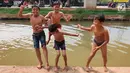 Anak-anak bermain dan berenang di Sungai Kalimalang, Jakarta Timur, Jumat (5/7/2019). Tingginya suhu udara Ibu Kota akibat musim kemarau menyebabkan anak-anak tersebut berenang di Sungai Kalimalang meski dengan kondisi seadanya. (Liputan6.com/Immanuel Antonius)