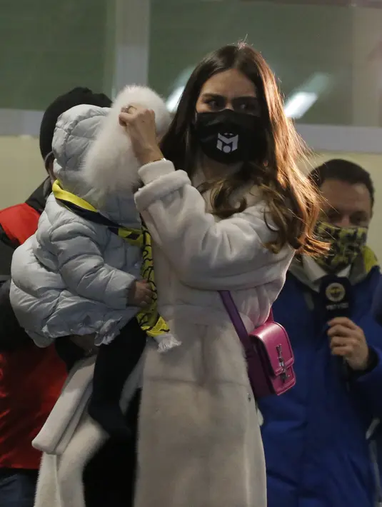 Amine Gulse, istri Mesut Ozil, menggendong putri mereka Eda, setelah tiba di Bandara Ataturk di Istanbul (18/1/2021). Fenerbahce pun kini mendapatkan Ozil dengan status bebas transfer. Ozil bakal pakai nomor punggung 67 di klub asal Istanbul tersebut. (AP Photo)