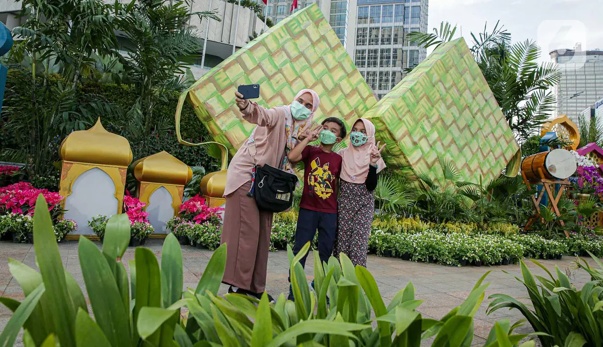 <p>Sejumlah warga berfoto dengan dekorasi bertemakan Idul Fitri di kawasan Bundaran HI, Jakarta, Rabu (27/4/2022). Dekorasi berbentuk masjid, ketupat, dan bedug yang dihiasi oleh tanaman tersebut dalam rangka menyambut Idul Fitri 1443 Hijriah. (Liputan6.com/Faizal Fanani)</p>