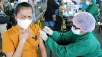 Seorang wanita menerima vaksin virus corona COVID-19 AstraZeneca di klinik vaksinasi massal darurat di Denpasar, Bali, Selasa (6/7/2021). Indonesia tengah memerangi gelombang infeksi baru yang belum pernah terjadi sebelumnya. (SONNY TUMBELAKA/AFP)