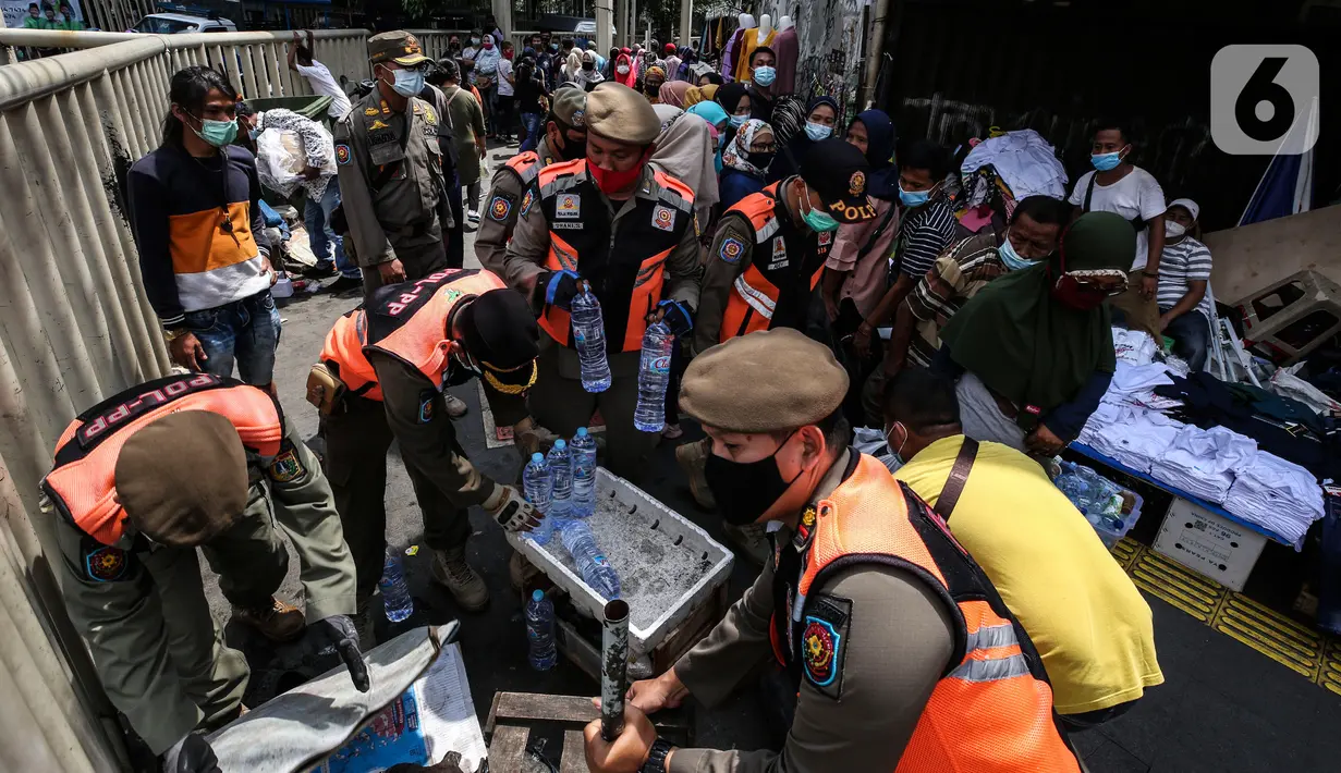 Aparat gabungan mengangkut dagangan pedagang yang berjualan di trotoar di kawasan Tanah Abang, Jakarta, Minggu (2/5/2021). Selain merazia barang dagangan pedagang, aparat gabungan juga menegur warga yang tidak menerapkan protokol kesehatan. (Liputan6.com/Johan Tallo)