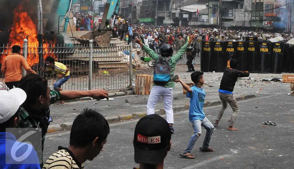 Massa menyerang Petugas kepolisian dan Satpol PP saat penggusuran Kampung Pulo, Jakarta, Kamis (20/8/2015). Penggusuran pemukiman Kampung Pulo dilakukan oleh 2.200 personel gabungan untuk normalisasi Sungai Ciliwung. (Liputan6.com/Herman Zakharia)
