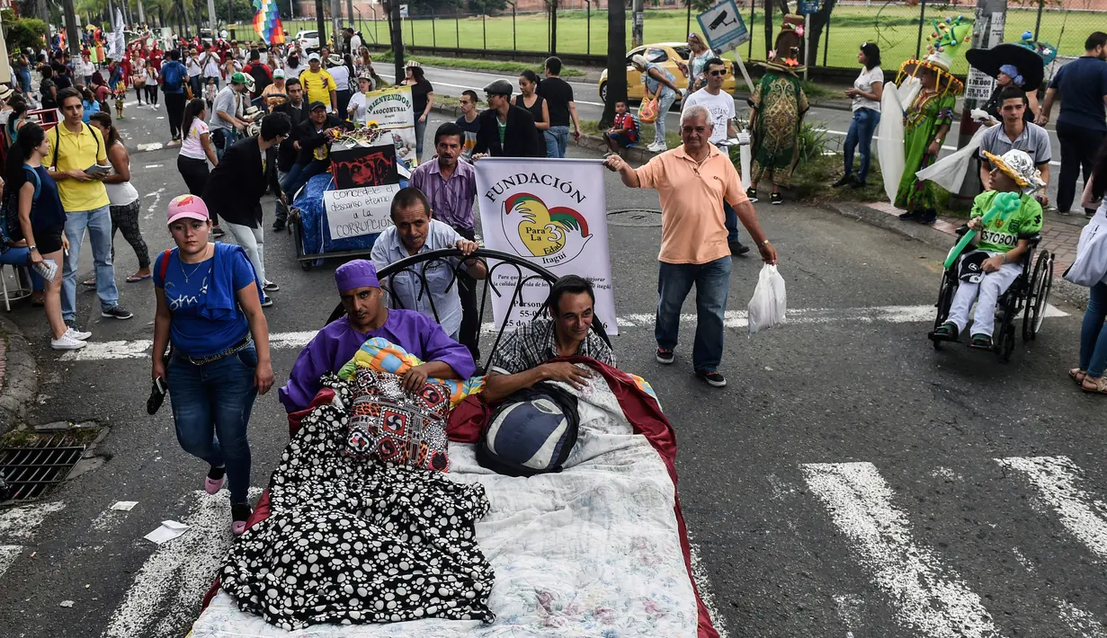 Warga Kolombia turun ke jalanan dan bermalas-malasan di atas tempat tidur dalam pawai untuk merayakan Hari Kemalasan Sedunia di Itagui, dekat Medellin, Minggu (19/8). Perayaan ini juga selalu penuh dengan antusiasme masyarakat. (AFP/JOAQUIN SARMIENTO)