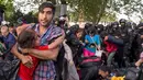 Seorang imigran menyelamatkan diri sambil menggendong anaknya di tengah bentrokan polisi dengan imigran yang berusaha menerobos pintu perbatasan antara Serbia dan Hungaria di Roszke, Rabu (16/9/2015). (REUTERS/Marko Djurica)