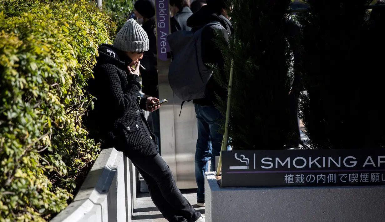 Seorang pria merokok di smoking area yang disediakan di Naka-Meguro, Tokyo (10/3). Kesadaran warga Jepang termasuk tinggi dengan tertibnya para perokok yang tidak merokok di sembarang tempat. (AFP Photo/BEHROUZ MEHRI)