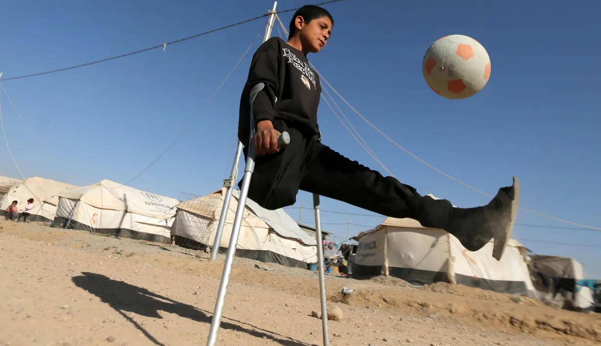 Pengungsi anak Irak Jasim Abudllah Jasim, 13, yang menurut keluarganya kehilangan kakinya dalam serangan udara di Baiji, memainkan sepak bola di Debaga kamp, di pinggiran Erbil, Irak November (24/11). (REUTERS/Mohammed Salem) 