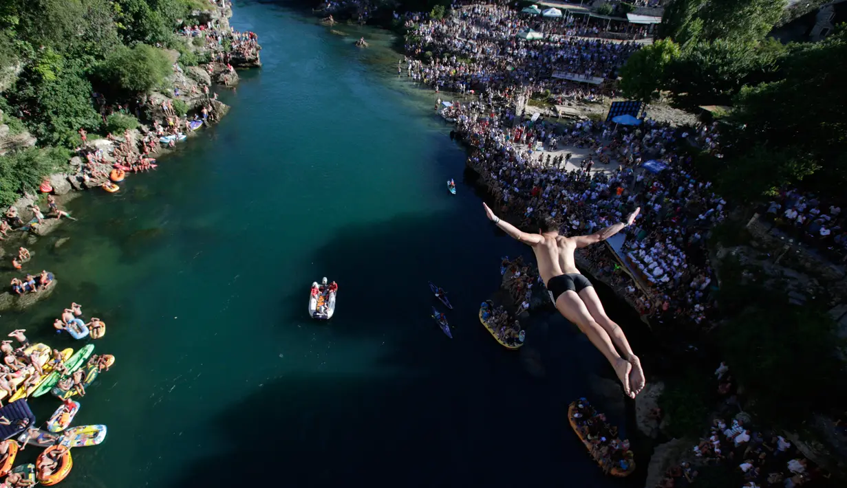 Peserta melakukan lompatan dari atas jembatan Mostar selama kompetisi menyelam tradisional ke 451 di Mostar, Bosnia, Minggu (30/7). Para peserta dari Bosnia dan negara-negara tetangga itu melakukan lompatan dari ketinggian 25 meter. (AP Photo/Amel Emric)