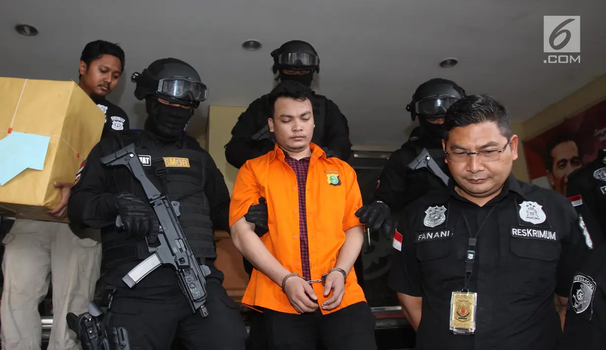 Tersangka pembunuh satu keluarga di Bekasi Haris Simamora (tengah) mendapat pengawalan polisi bersenjata di Polda Metro Jaya, Jakarta, Kamis (21/2). Haris segera diseret ke meja hijau untuk mempertanggungjawabkan perbuatannya. (Merdeka.com/Imam Buhori)
