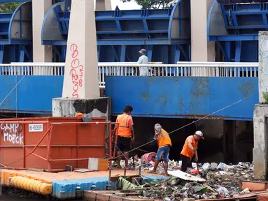 Petugas dari Dinas Kebersihan mengangkut sampah yang tersangkut di Pintu Air, Jakarta, Jum'at (30/9). Perawatan Pintu Air dari tumpukan sampah yang tersangkut agar buka tutup pintu air Jembatan Hanging dapat maksimal. (Liputan6.com/Johan Tallo)