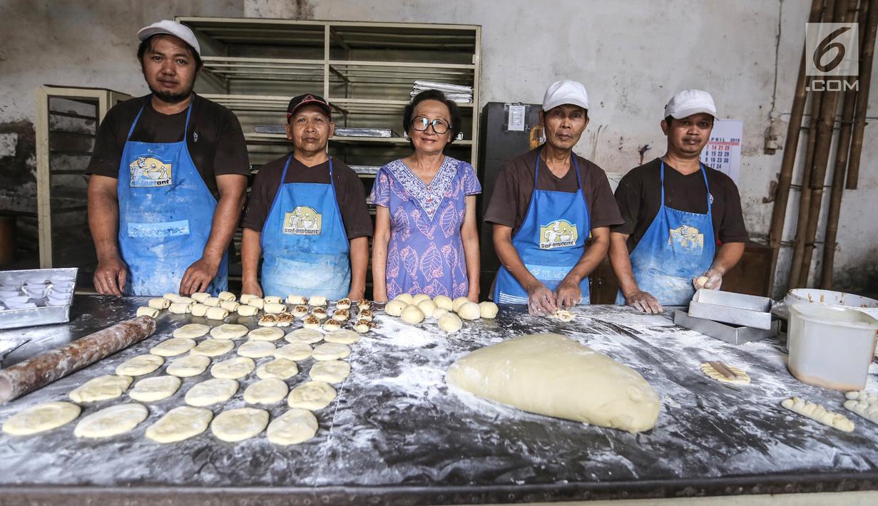 Rosani, generasi ketiga (tengah) foto bersama dengan sejumlah karyawan di Toko Roti GO, Purwokerto, Jawa Tengah, Senin (22/4). Memasuki usia ke 121 tahun, toko roti yang berdiri sejak tahun 1898 ini dibuat mengunakan peralatan tradisional dan tanpa bahan pengawet. (Liputan6.com/Fery Pradolo)