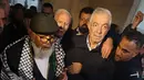 Narapidana Palestina tertua yang ditahan di penjara Israel (kiri) berdoa di atas makam mendiang pemimpin Palestina Yasser Arafat di kota Ramallah, Tepi Barat, Senin (13/3/2023).  Fuad Shubaki (83) dijatuhi hukuman 20 tahun penjara, yang kemudian dikurangi menjadi 17 tahun. (Photo by AHMAD GHARABLI / AFP)