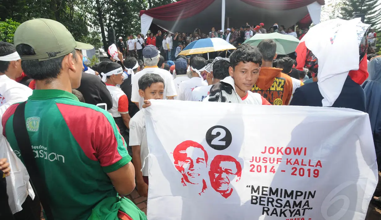 Seorang simpatisan terlihat membawa spanduk Jokowi-JK di lapangan Situ Buleud di Kabupaten Purwakarta, Jawa Barat, Selasa (17/6/14). (Liputan6.com/Herman Zakharia)