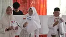 Calon wakil presiden no urut 01 Ma’ruf Amin didampingi istri Wury Estu Handayani dan putrinya menunjukkan surat suara usai mencoblos di TPS 051 Koja, Tanjung Priok, Jakarta, Rabu (17/4). Ma’ruf Amin tiba bersama keluarga menggunakan baju koko putih, kopiah dan sorban. (merdeka.com/Iqbal S. Nugroho)