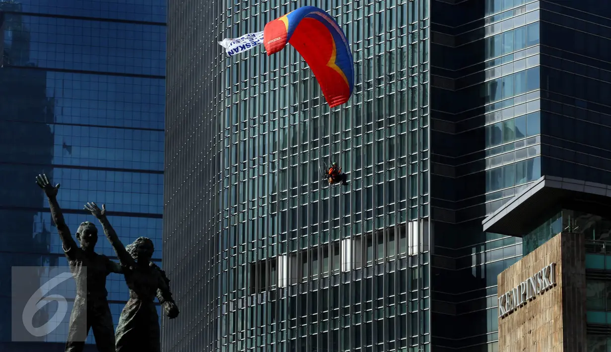 Aksi paramotor saat parade bendera peserta Sidang Umum Interpol Ke-85 di kawasan Bundaran HI, Jakarta, Minggu (30/10).  (Liputan6.com/Johan Tallo)