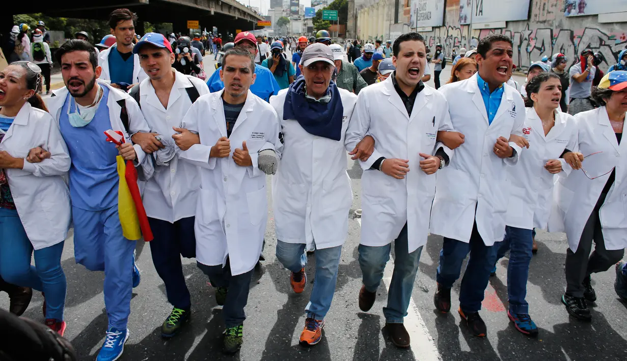 Para dokter berbaris saat unjuk rasa menuntut Presiden Venezuela Nicolas Maduro di Caracas, Venezuela, (22/5). Selama dua bulan Sedikitnya 46 orang telah meninggal saat unjuk rasa terjadi di Venezuela. (AP Photo/Ariana Cubillos)