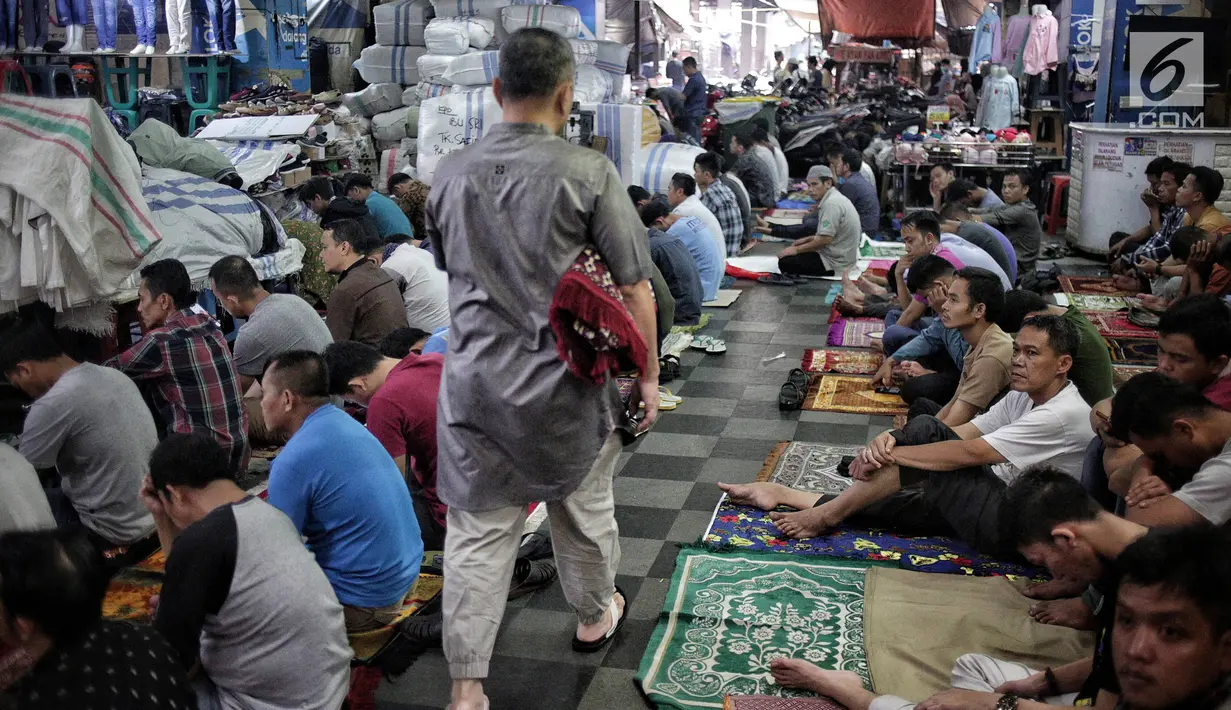 Seorang pria berjalan melintasi jemaah saat akan melaksanakan salat Jumat di Pasar Tanah Abang, Jakarta, Jumat (10/5/2019). Area masjid yang terbatas membuat jemaah harus mengisi selasar dan lorong di area pasar untuk menjalankan salat. (Liputan6.com/Faizal Fanani)