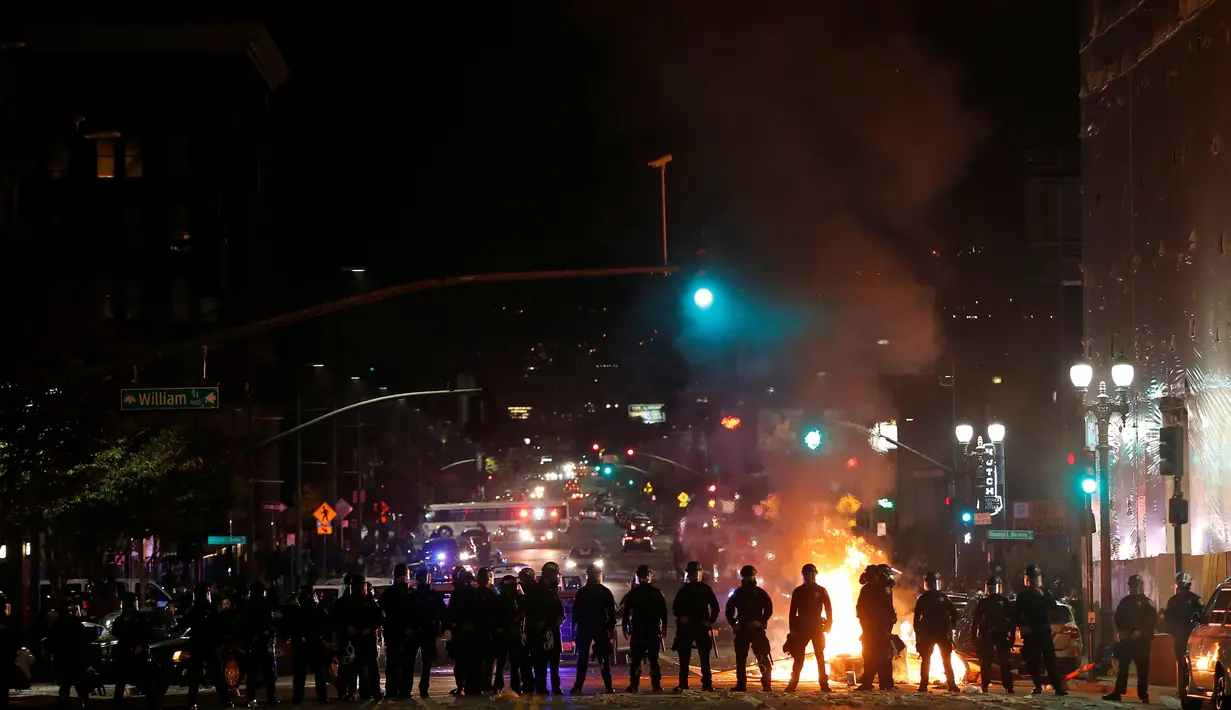 Petugas kepolisian membentuk barikade mengamankan aksi pengunjuk rasa yang membakar ban di tengah jalan Oakland, California, Rabu (9/11). Unjuk rasa merebak di seluruh wilayah Amerika Serikat, menyusul kemenangan Donald Trump. (REUTERS / Stephen Lam)