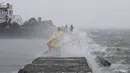 Sejumlah warga berjalan di tengah hujan lebat saat badai topan Linfa disertai gelombang laut menghantam Teluk Manila, Filipina, Senin (6/7/2015). Akibat badai aktivitas penerbangan, pelabuhan dan sekolah-sekolah ditutup. (REUTERS/Romeo Ranoco)