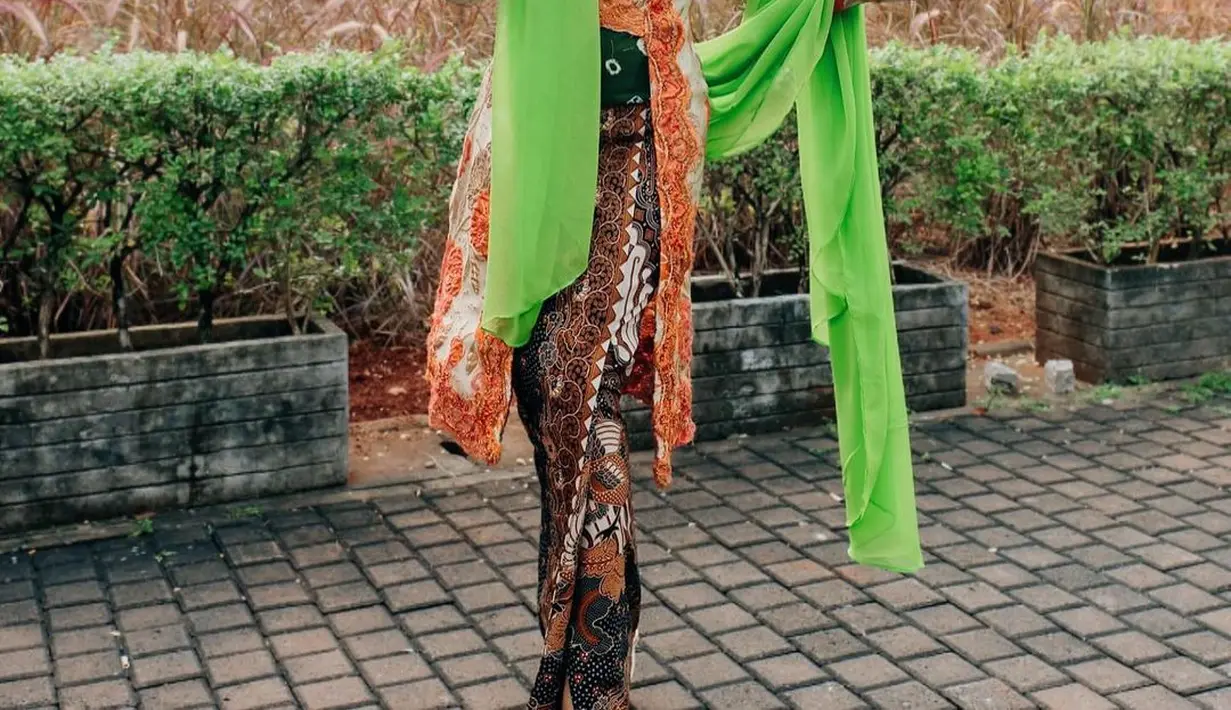 Yuni Shara tampil ayu kenakan kebaya floral oranye. Tampilannya meriah dengan paduan kain batik dan selendang hijau neon [@yunishara36]