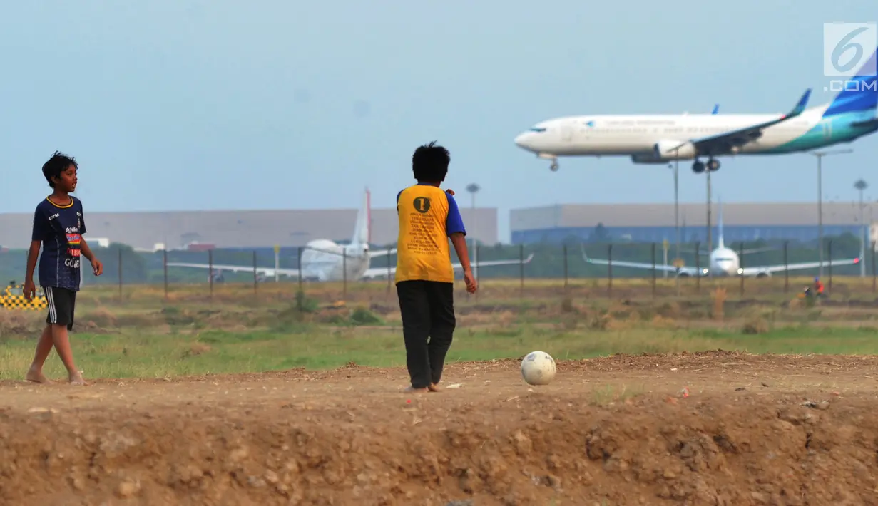Anak-anak bermain bola di kawasan proyek perluasan landasan pacu atau Runway 3A Bandara Soekarno-Hatta (Soetta), Rawa Bokor, Tangerang, Banten, Selasa (2/7/2019). Mereka memanfaatkan lahan kosong yang belum dikerjakan pihak kontraktor untuk bermain bola. (merdeka.com/Arie Basuki)