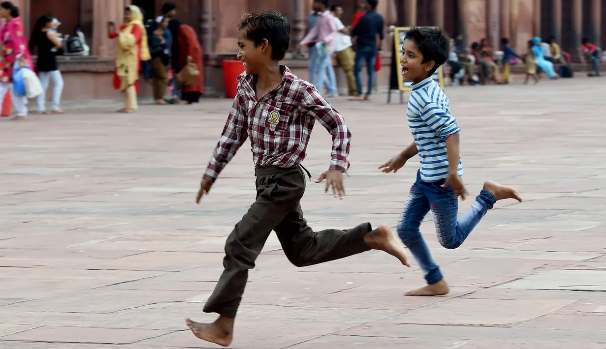 Anak-anak India bermain di masjid Masjid Jama di kawasan lama New Delhi (30/7/2019). Masjid ini didirikan oleh Kaisar Mogul, Syah Jehan, yang juga membangun Taj Mahal. (AFP Photo/Money Sharma)