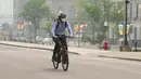 <p>Seorang pengendara sepeda memakai masker saat kualitas udara yang buruk karena asap dari kebakaran hutan di Ontario dan Quebec di Ottawa, Kanada, Selasa (6/6/2023). (Sean Kilpatrick/The Canadian Press via AP)</p>