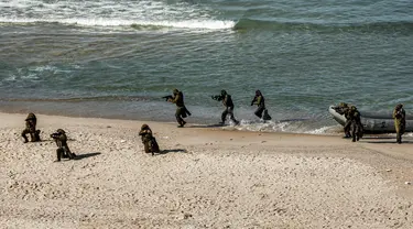 Pejuang bersenjata turun dari perahu karet di pantai selama latihan militer di Kota Gaza (29/12/2020).  Untuk pertama kalinya, Hamas bersama sayap militer kelompok-kelompok perlawanan Palestina lainnya menggelar latihan perang gabungan. (AFP/Mohammed Abed)