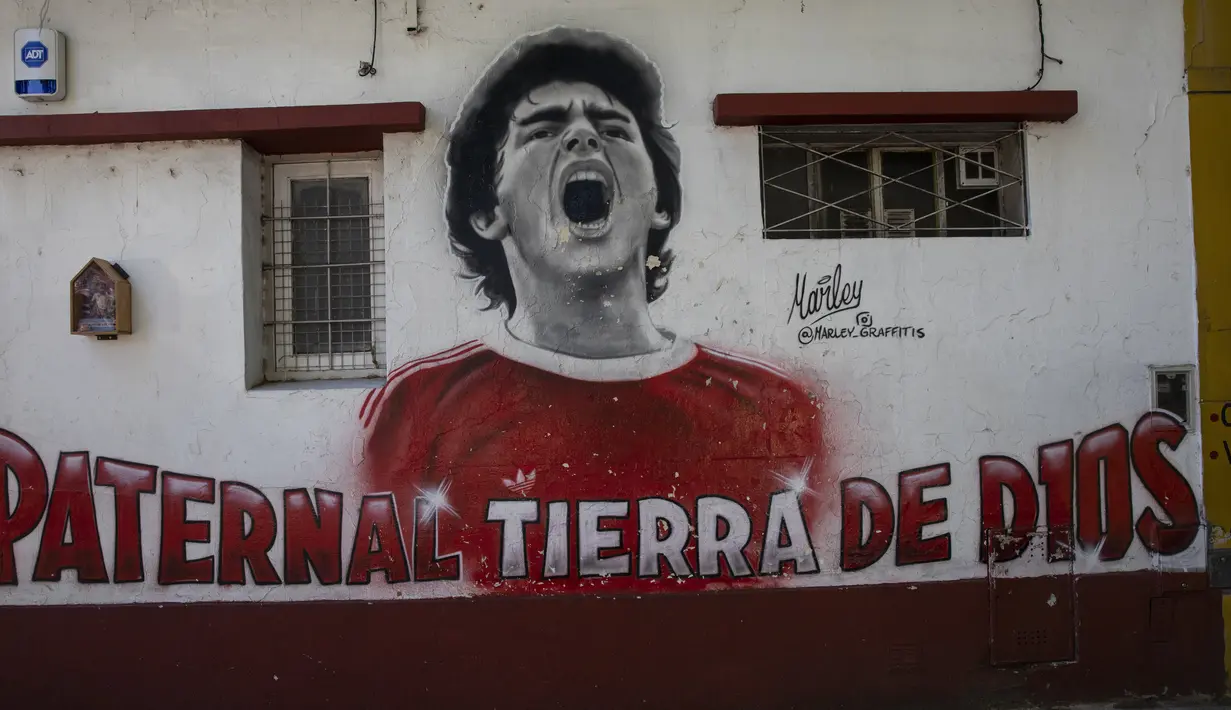 Sebuah mural dari mendiang bintang sepak bola Diego Maradona menutupi dinding dekat stadion Argentinos Juniors di Buenos Aires, Argentina, Selasa, (23/112021). Peringatan pertama kematian Maradona digelar pada 25 November 2021. (AP Photo/Rodrigo Abd)