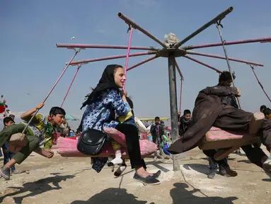 Anak-anak bermain ayunan selama perayaan Nowruz, Tahun Baru Persia, di Kabul, Afghanistan, (21/3). Nowruz dirayakan pada hari pertama musim semi di negara-negara termasuk Afghanistan, Tajikistan, dan Iran. (AP Photo/Rahmat Gul)