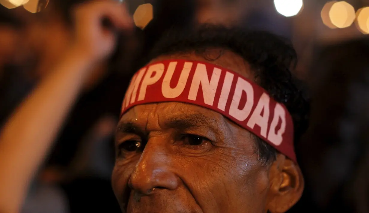 Seorang demonstran mengenakan ikat kepala yang bertuliskan "Impunity" saat berujuk rasa menuntut presiden Honduras,  Juan Hernandez untuk mundur atas dugaan korupsi senilai  US$ 200 juta di Tegucigalpa, Jumat (24/7/2015).  (REUTERS/Jorge Cabrera)